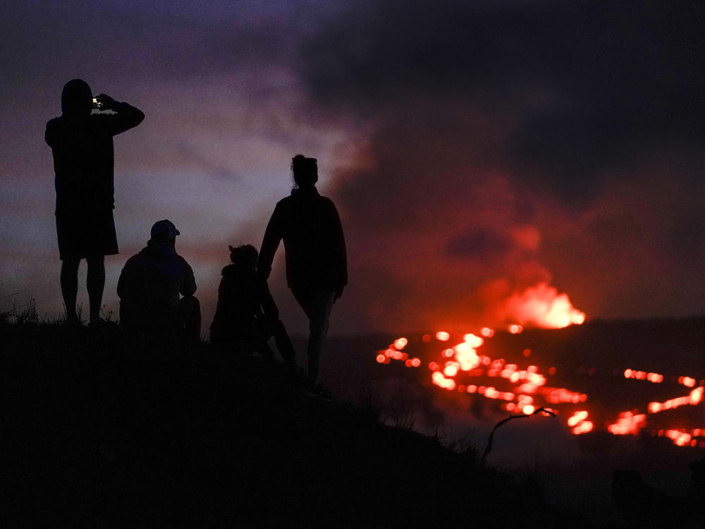 People watch lava from the Mauna Loa volcano on Dec. 1. U.S. scientists declared Tuesday that two active Hawaii volcanoes — one where lava destroyed hundreds of homes in 2018 and another where lava recently stalled before reaching a crucial Big Island highway — have stopped erupting.