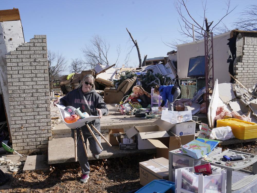 Belinda Penner carries belonging from her cousin's home, destroyed by a tornado, Tuesday, in Wayne, Okla.
