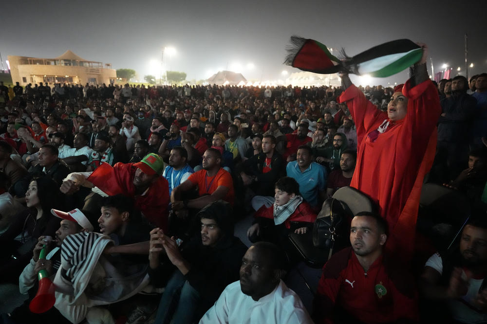 Morocco's fans, one waving a Palestinian flag, watch a World Cup semifinal match with France on Wednesday, Dec. 14, outside the Al Bayt Stadium in Doha, Qatar.