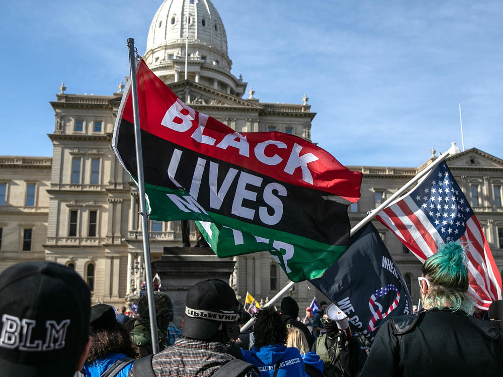 Counter-protesters carrying Black Lives Matter flags walk past a group of Trump supporters at the Michigan State Capitol building in November 2020 in Lansing, Mich.