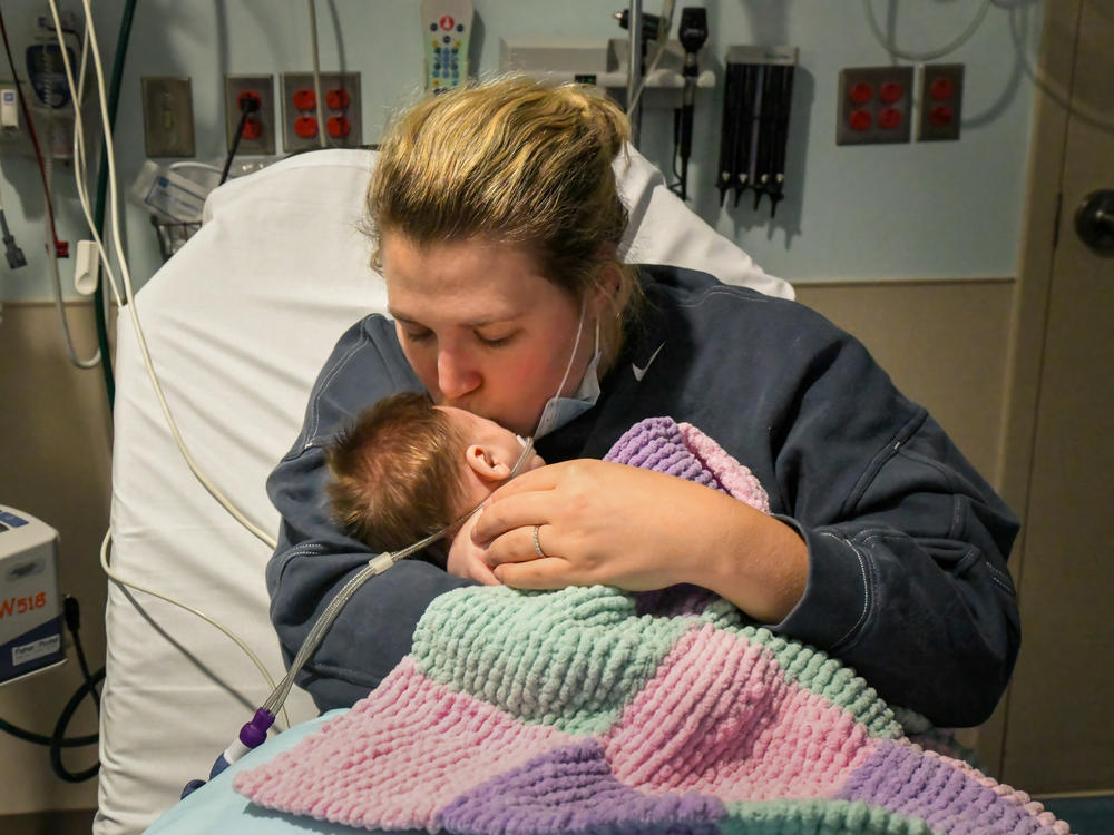 Caitlyn Houston kisses her seven-week-old daughter, Parker, as they wait in the ER for a hospital bed to open up on Dec. 7 at Corewell Health Helen DeVos Children's Hospital in Grand Rapids, Michigan. 
