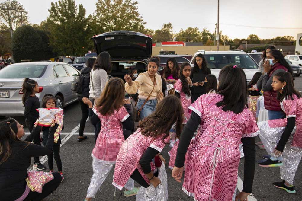 Children from the Bollywood-style dance group Rhythmaaya get ready to participate in an annual Halloween parade in Vienna, Va., on Oct. 27, 2021. The dancers' mothers help their children get ready in a nearby parking lot.