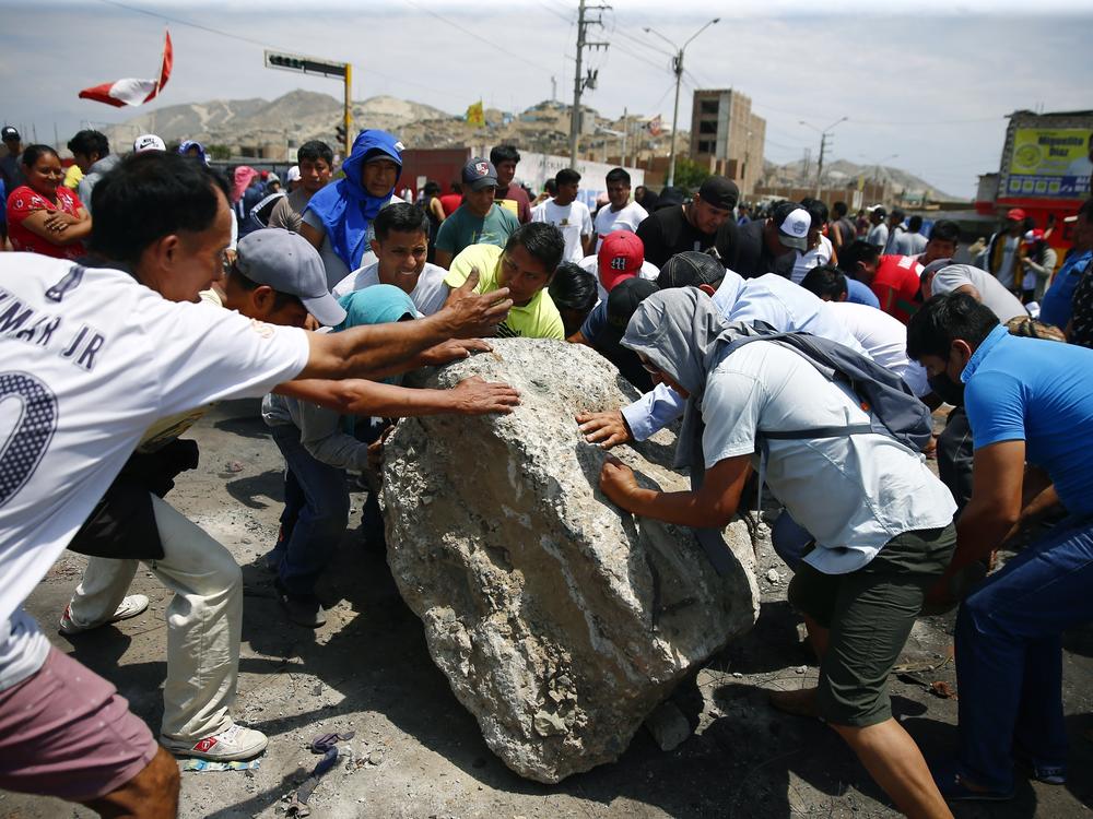 Supporters of ousted Peruvian President Pedro Castillo work together to roll a boulder onto the Pan-American North Highway during a protest against his detention, in Chao, Peru, on Thursday.