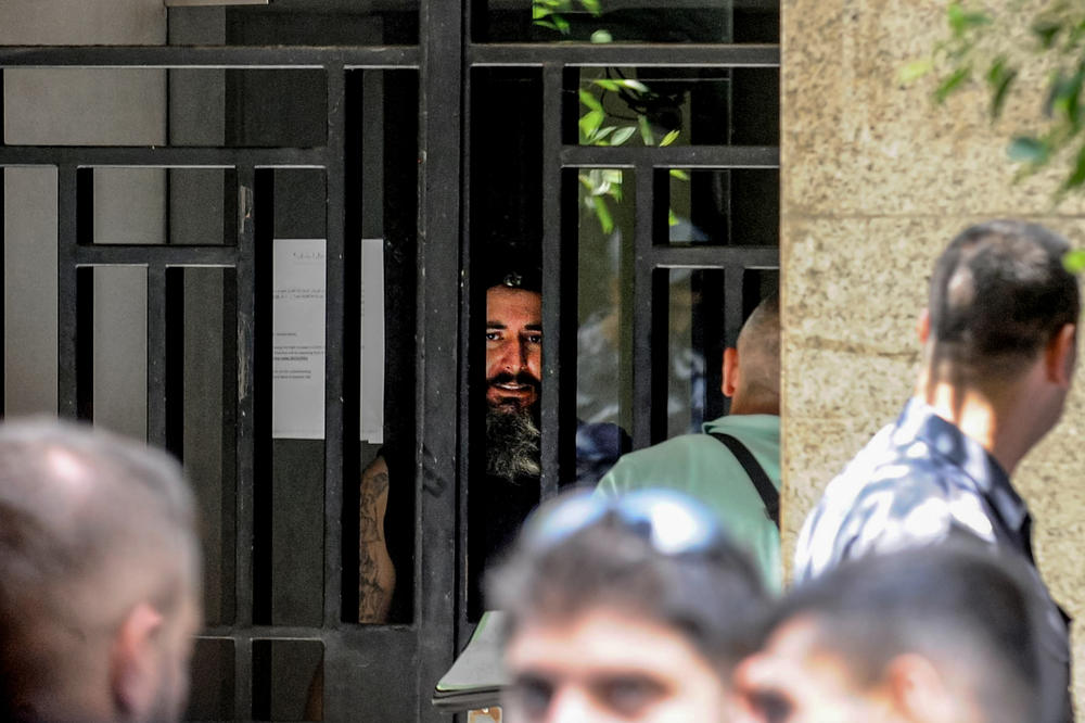 A man speaks to negotiators from behind the iron bars of a local bank in Beirut, Lebanon, on Aug. 11, after he stormed the branch and held employees and customers as hostages. The man, who entered the bank carrying a machine gun and gasoline, demanded part of his deposited money, amounting to $209,000.