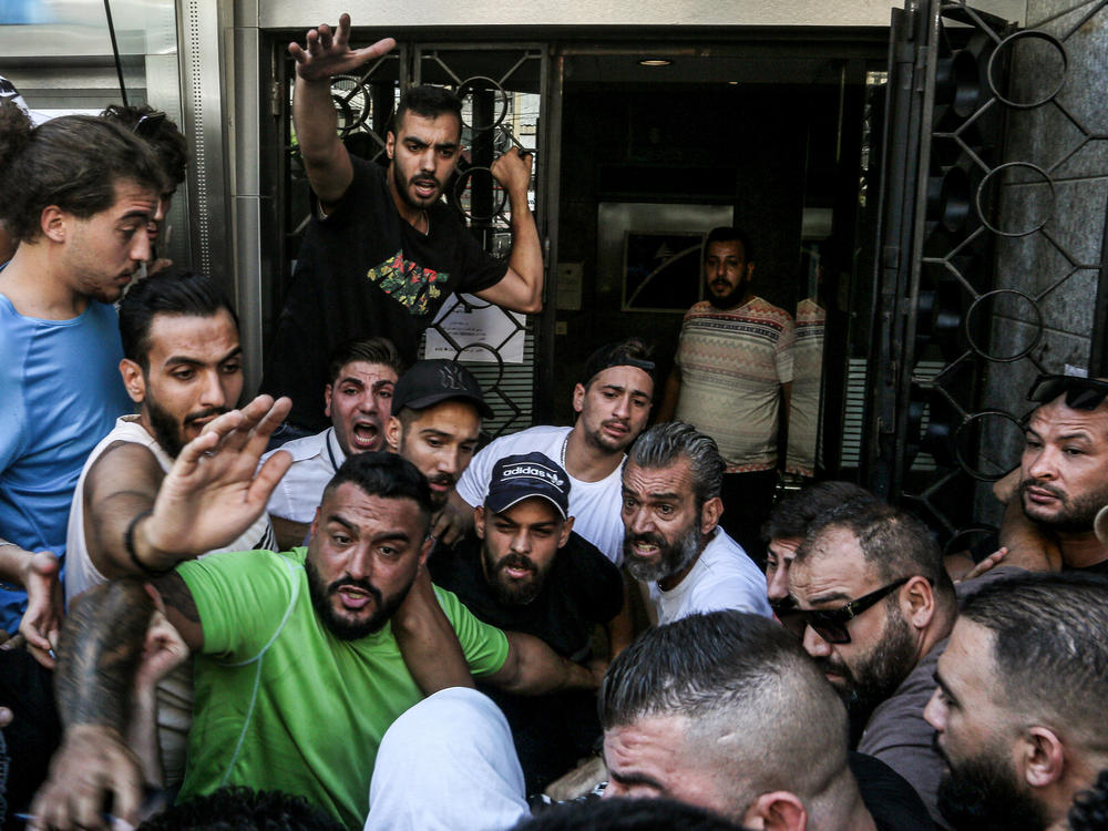 Lebanese activists gather outside a local bank in support of Abed Soubra, who stormed the branch demanding access to his own accounts, in Beirut on Sept 16. Lebanese police detained Soubra after he entered the bank and, armed with a gun, demanded access to his deposits. It was the third such incident in Lebanon that week alone.