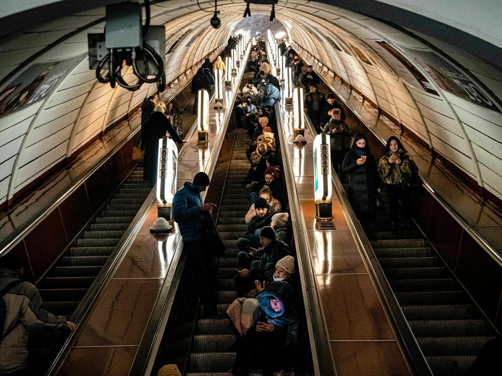Civilians sit on an escalator while taking shelter inside a metro station during an air raid alert in the center of Kyiv on Dec. 16, 2022. A fresh barrage of Russian strikes hit cities across Ukraine early on Friday.