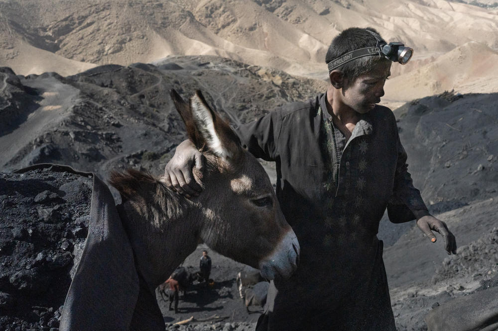 A boy guides a loaded donkey over paths on the steep mountain where the coal mine is located.