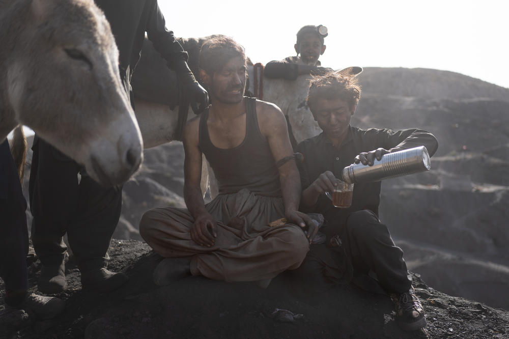 Miners take a break with their donkeys and drink tea near the end of a shift.