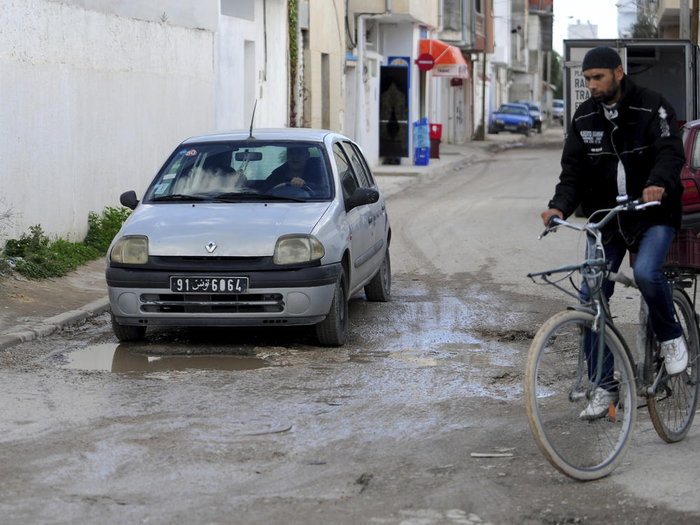 A man drives a car in a damaged street of La Marsa, outside Tunis, Wednesday, Dec. 14, 2022. To outsiders, Tunisia's legislative elections Saturday, Dec. 17, 2022 look questionable: Many opposition parties are boycotting. A new electoral law makes it harder for women to compete. Foreign media aren't allowed to talk to candidates.