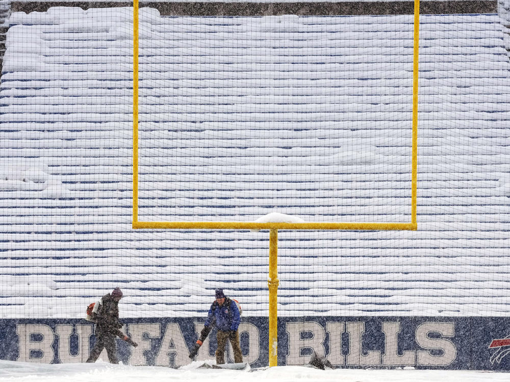 Grounds crew work to clear snow off the field at Highmark Stadium before an NFL football game between the Buffalo Bills and the Miami Dolphins in Orchard Park, N.Y., Saturday, Dec. 17, 2022.