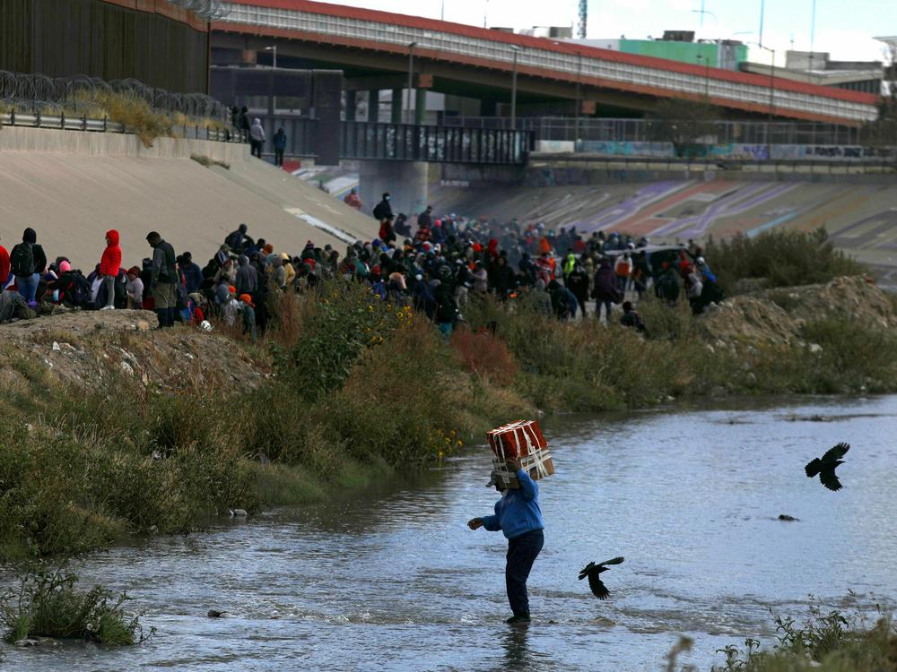 Migrants walk across the Rio Grande to surrender to US Border Patrol agents in El Paso, Texas, as seen from Ciudad Juarez, Chihuahua state, Mexico, on December 13, 2022. (Photo by Herika Martinez / AFP)