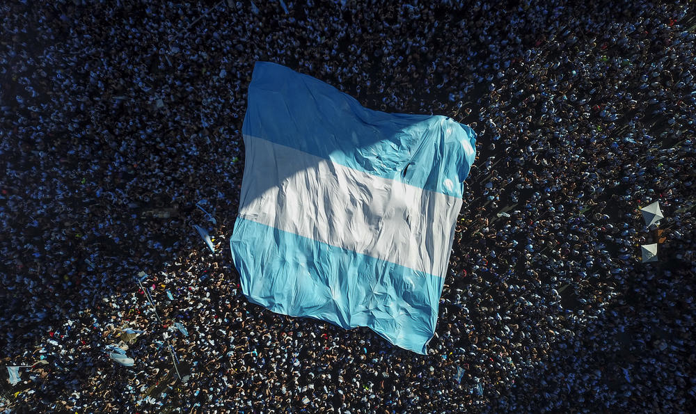 Soccer fans hold up a flag of Argentina while celebrating the team's 2022 World Cup win over defending champions France in downtown Buenos Aires on Sunday, Dec. 18.