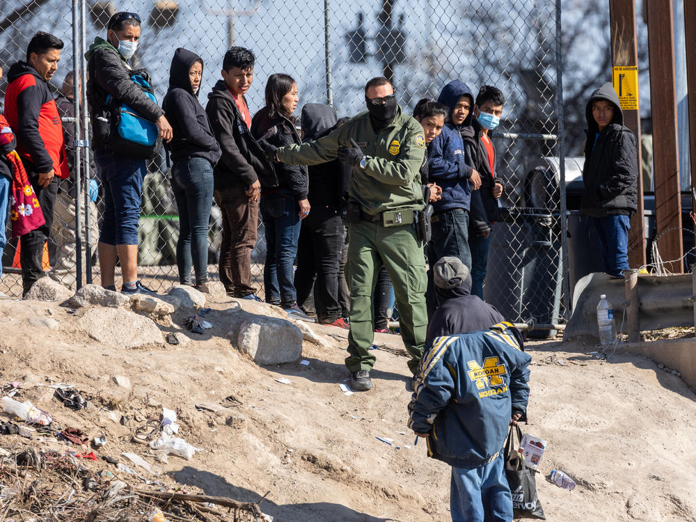 A U.S. Border Patrol agent instructs immigrants who had crossed the Rio Grande into El Paso, Texas on Dec. 19, as seen from Ciudad Juarez, Mexico. Over the weekend, El Paso declared a state of emergency, one week after a surge of asylum seekers began crossing the border, quickly overwhelming federal immigration and city authorities.