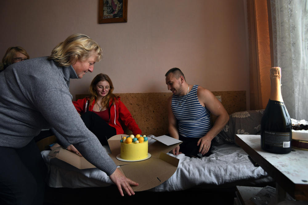 Misha's mother, Halyna Varvarych, 51, brings a cake decorated with the colors of the Ukrainian flag as he celebrates his 28th birthday with family and friends.
