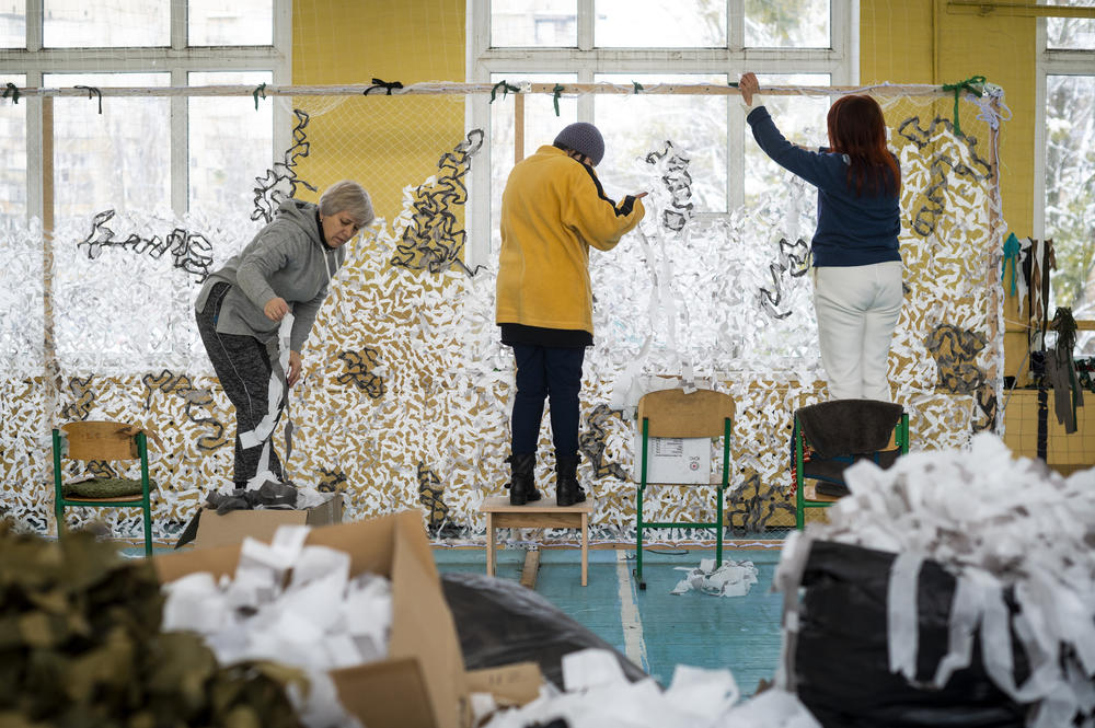 Volunteers in a school gymnasium in the Kyiv suburb of Bucha weave camouflage netting for use by the military, on Dec. 2. The group said they have created over 4,000 square yards of netting since starting their project after the liberation of Bucha. They have also created 8 sniper suits, known as 