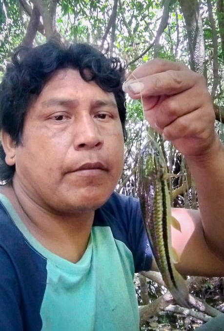 Takakre holds up a small <em>jejú</em> fish caught during a fishing trip on the Pixaxá River.