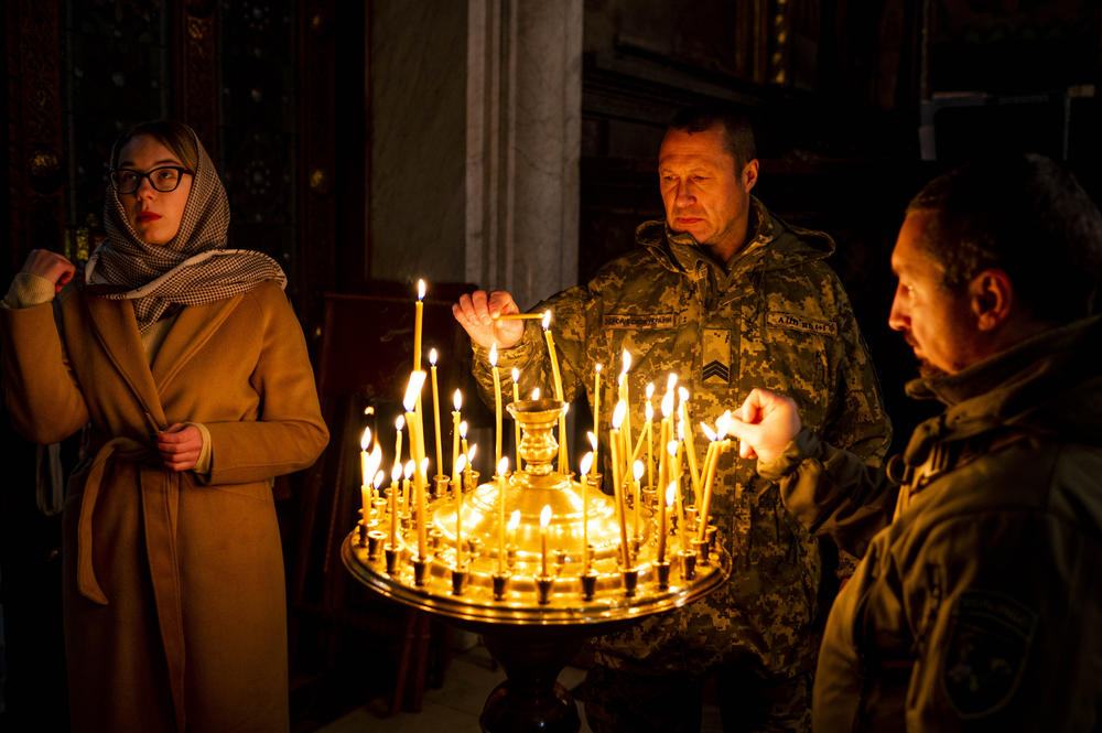 Soldiers light candles to honor the dead as a woman crosses herself at a Sunday Mass celebrating the Presentation of the Virgin Mary at St. Volodymyr's Cathedral in Kyiv on Dec. 4.