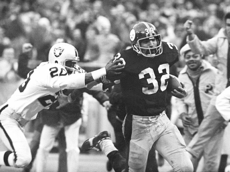 Pittsburgh Steelers' Franco Harris (32) eludes a tackle by Oakland Raiders' Jimmy Warren as he runs 42-yards for a touchdown after catching a deflected pass during an AFC Divisional NFL football playoff game in Pittsburgh in 1972. Harris died on Wednesday morning at age 72.