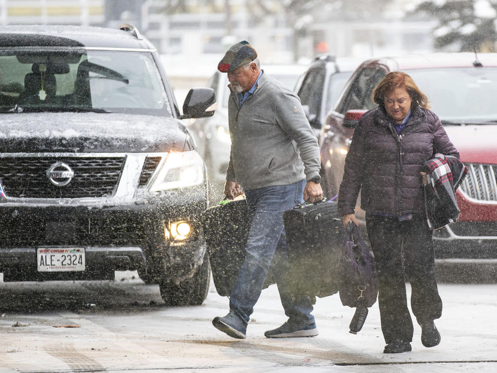 Travelers walk through the snow into Terminal 1 Wednesday, Dec. 21, 2022 at the Minneapolis-Saint Paul International Airport in Minneapolis.