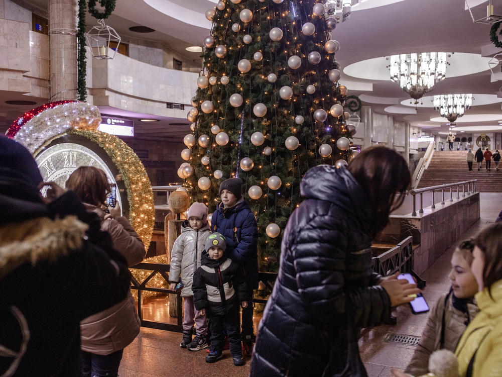 Children pose for photos in front of a Christmas tree and other holiday decorations in a metro station in Kharkiv, Ukraine, on Dec. 11.