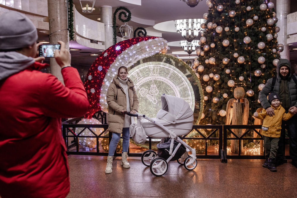 People pose for family photos in front of a Christmas tree and other decorations in a metro station in Kharkiv, Ukraine, on Dec. 11.