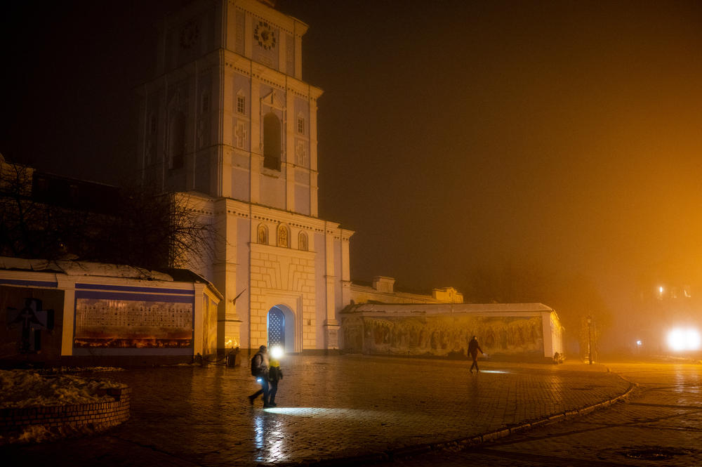 People use headlamps and flashlights as they pass St. Michael's Golden-Domed Monastery during a power outage in Kyiv on Dec. 10.