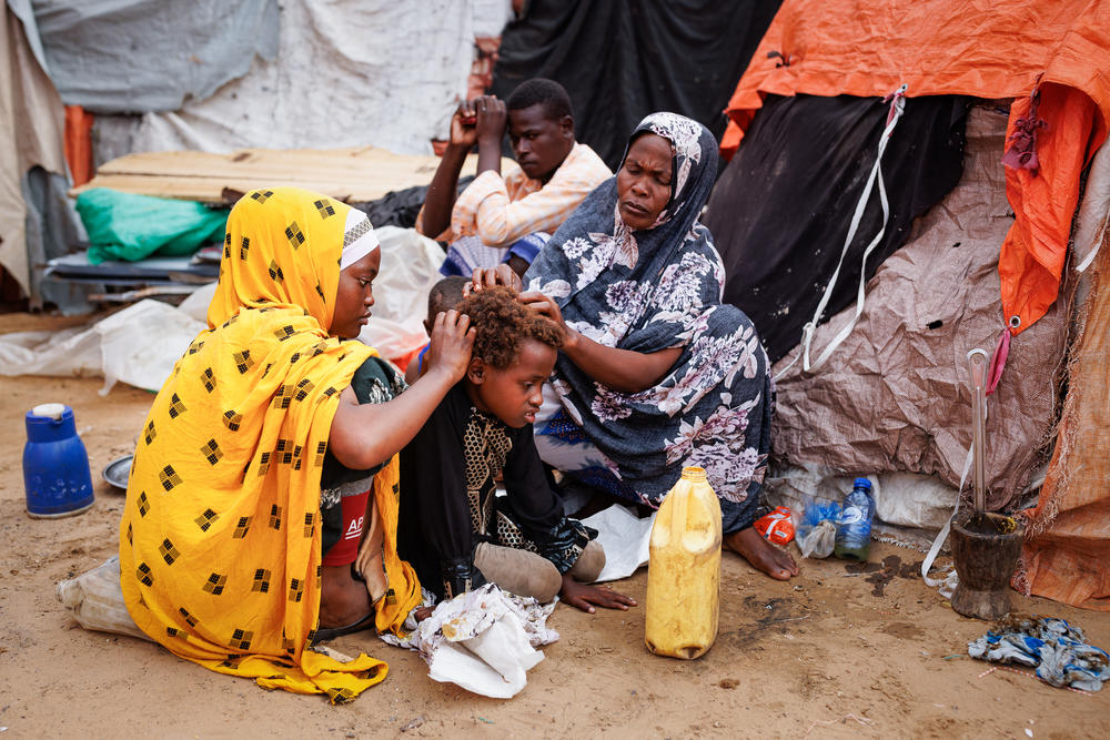 Khadijo Noor Ali (right) removes lice from the hair of 8-year-old Dahiro Ibrahim Adan, an orphaned relative whom the single mother of five is caring for. The faded reddish hue of the boy's hair is characteristic of a child who is malnourished.