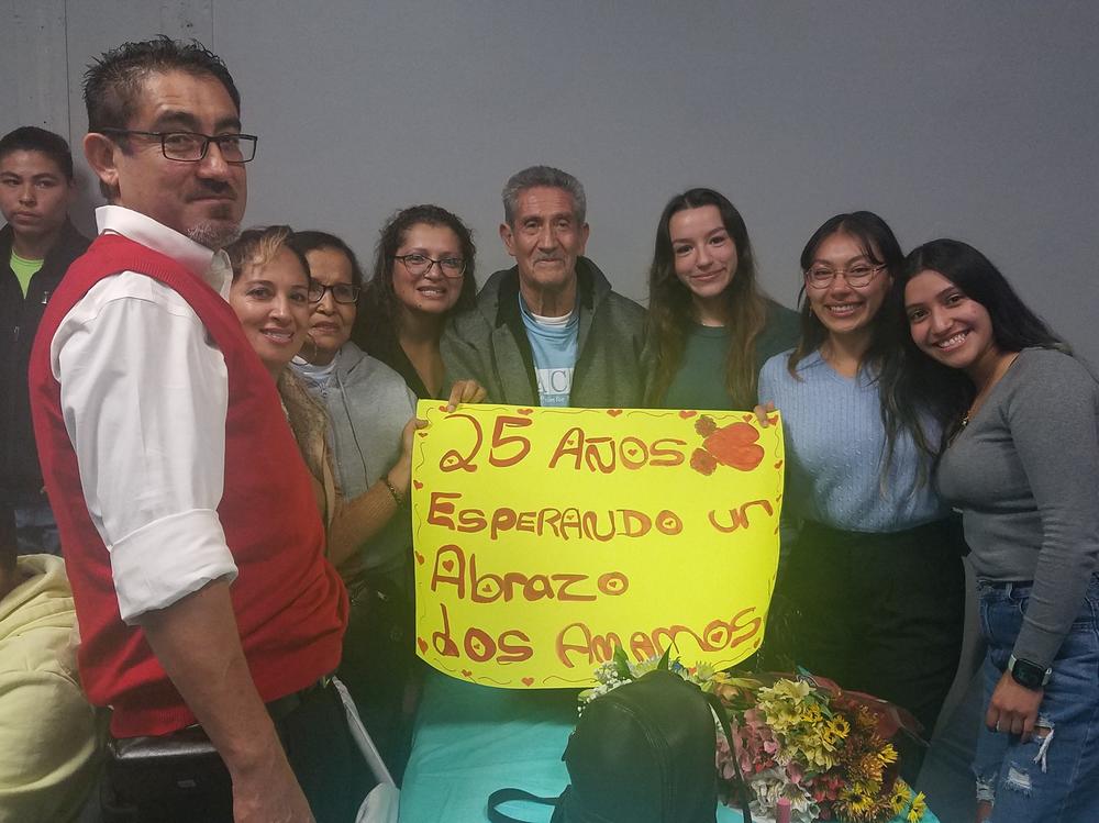 The Rodriguez Tellez family poses for a picture, together for the first time in 25 years. The sign says, 