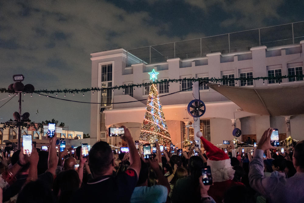 People photograph the Christmas tree after its lights are lit in the St. Mary's Catholic Church courtyard.