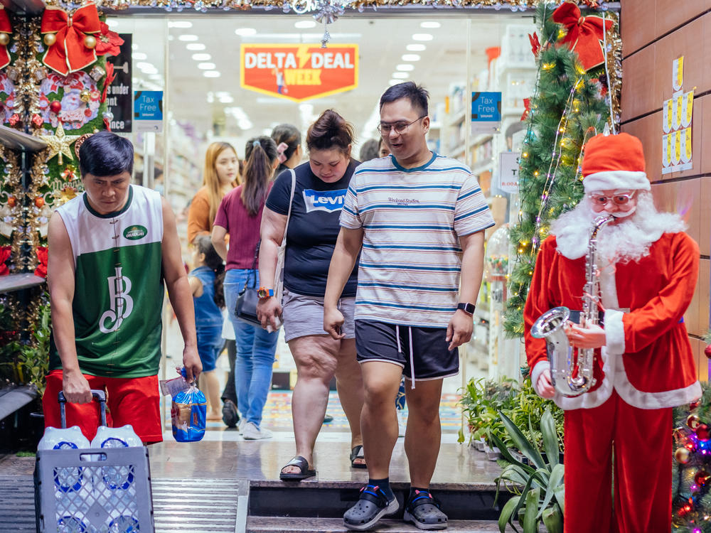 People leave a grocery store with Christmas decorations on Rigga Street in Dubai. Many Filipinos working in Dubai call this area home.