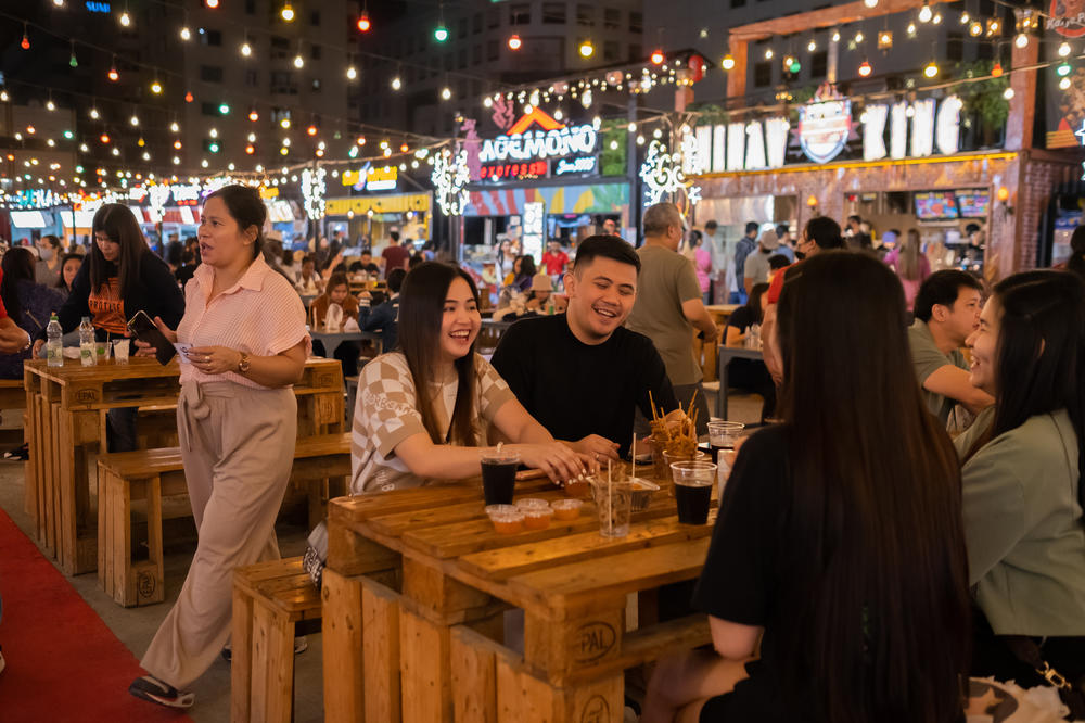 People eat outside at the night market on Rigga Street.