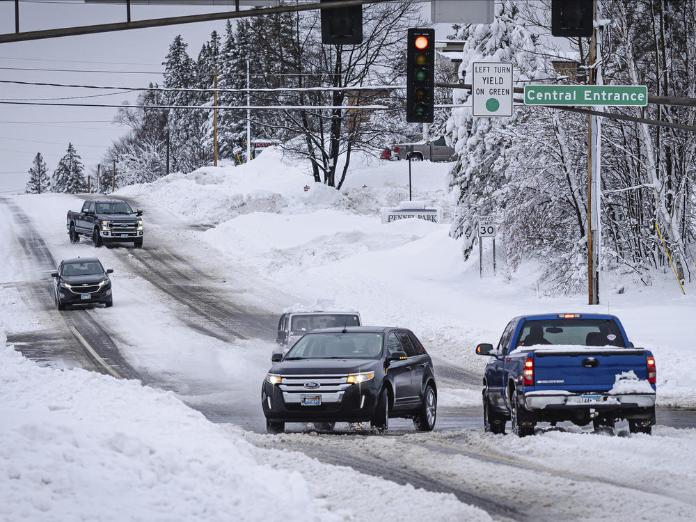 Cars slowly travel through an intersection after a second round of snow storm passed through northern Minnesota Thursday, Dec. 15, 2022, in Duluth, Minn.