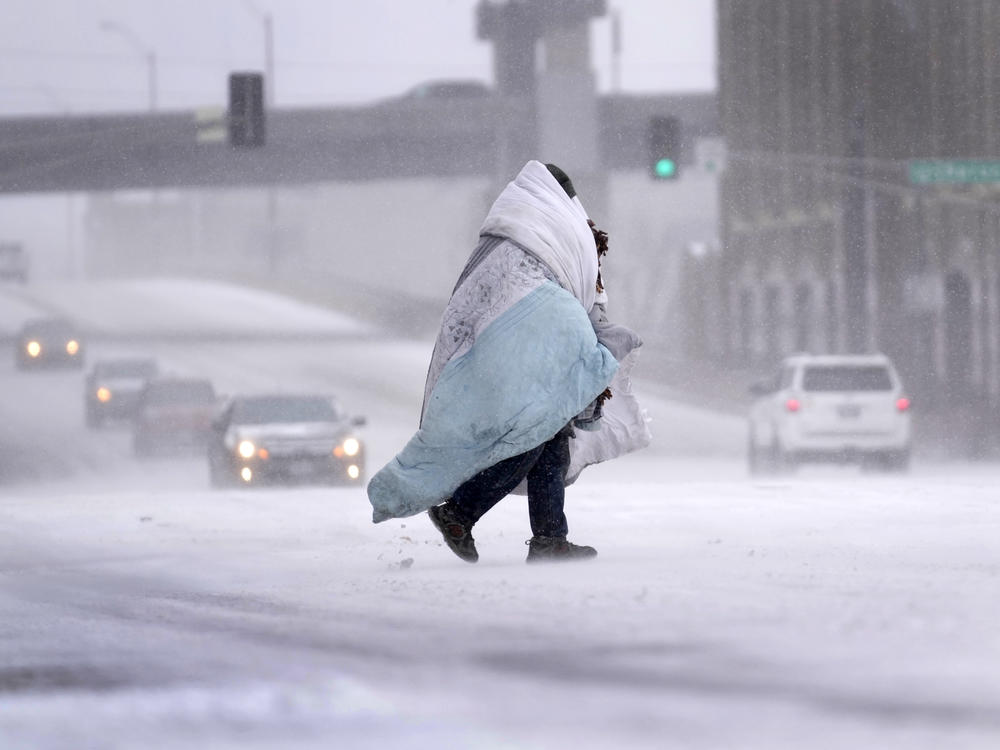 A person wrapped in a blanket crosses a snow-covered street Thursday in St. Louis.