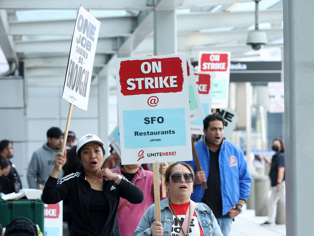 San Francisco International Airport food service workers carry signs as they strike outside of a terminal at the airport on September 26, 2022 in San Francisco, California.
