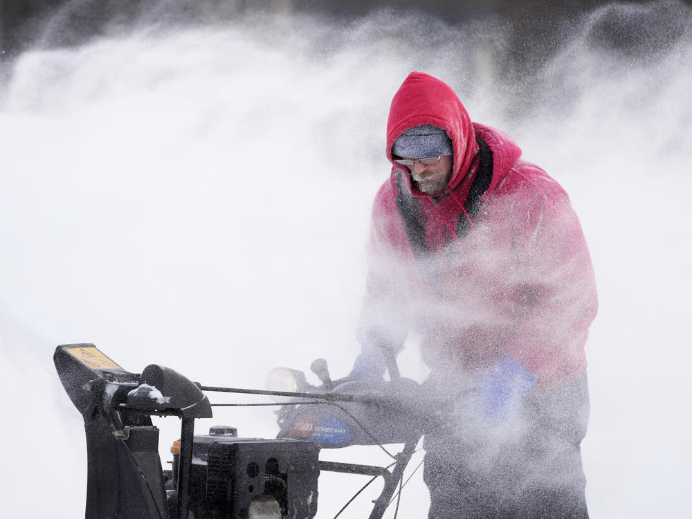 Mark Sorter clears snow on Friday from a downtown ice skating rink in Des Moines, Iowa.