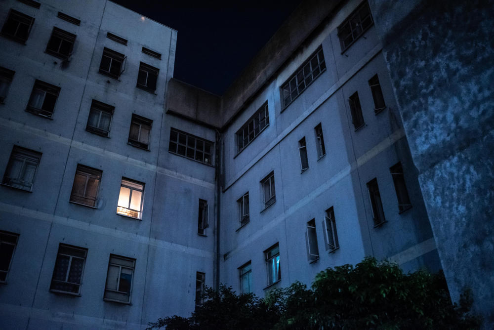 A light shines in a window of Ahmed Kathrada House, a former nursing home in inner-city Cape Town that is now home to a community of several hundred families. The building lacks electricity and running water, but residents say it is preferable to living on the edge of the city without access to jobs.