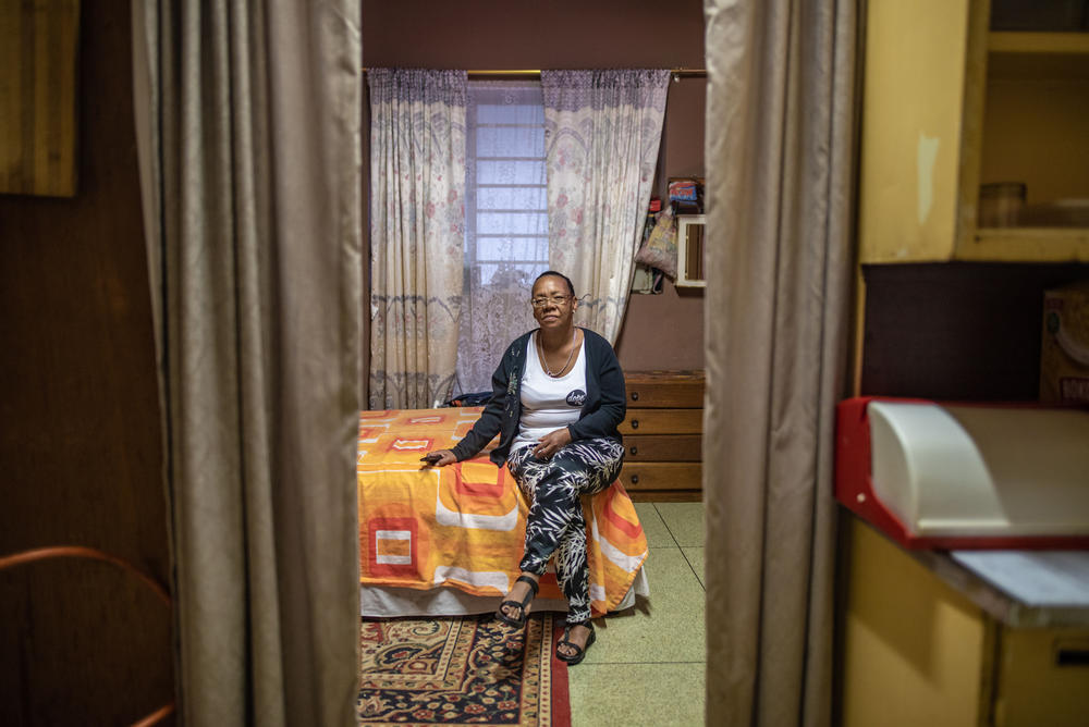 Elizabeth Daniels, 52, photographed in her room at Cissie Gool House, has used plywood panels and fabric to divide up her room and make it feel more like a home.