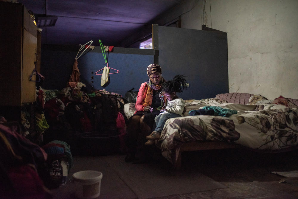 Lillian Mvolontshi and her granddaughter, Phawu, watch a video on a phone in the abandoned military warehouse where they now live in central Cape Town. While living in the Cape Flats, she was spending most of her income on transport, and was frequently faced with the threat of violence at home and on her daily commute.