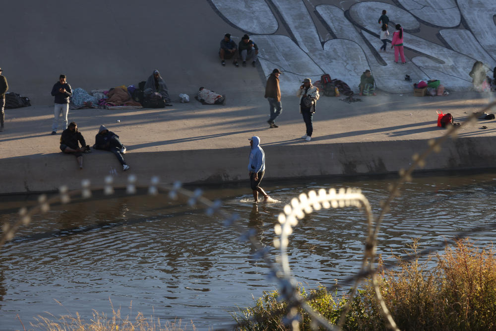 Some asylum-seeking migrants and others wait on the Mexico side of Rio Grande River while others attempt to cross the border into the United States in El Paso, Texas, U.S., December 21, 2022.