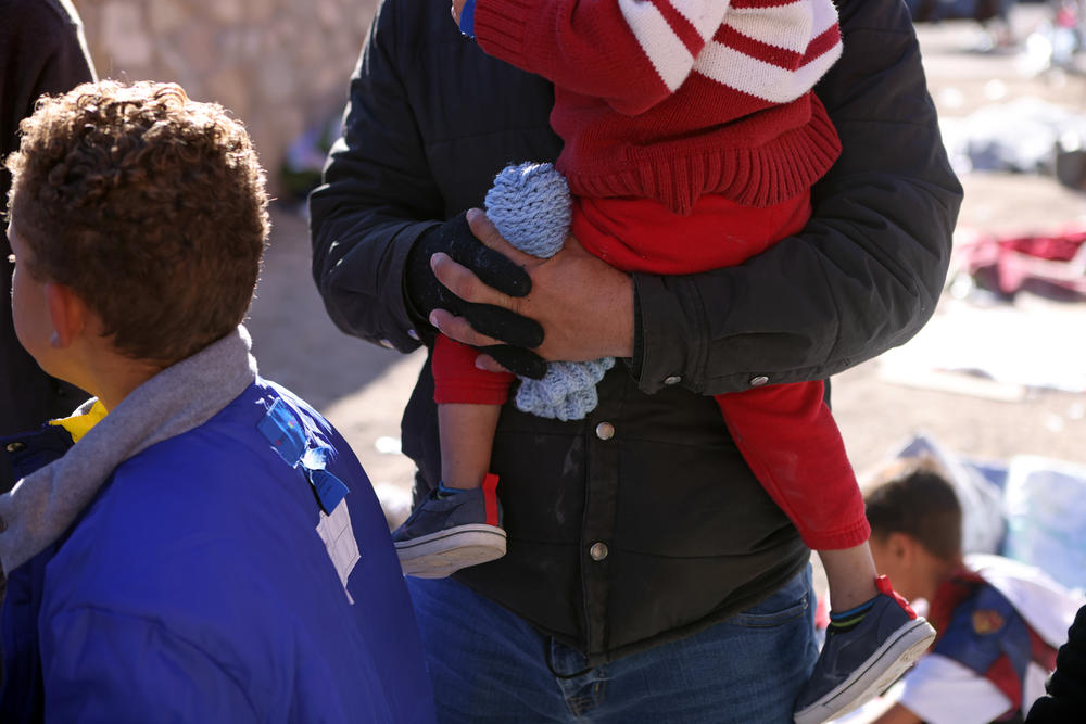 An asylum-seeking migrant from Valenzuela holds one of his for sons as he is living unsheltered with his wife after crossing the Rio Grande River into the United States in El Paso, Texas, U.S., December 22, 2022.