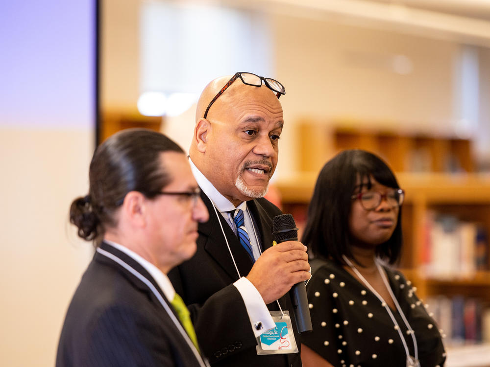 Anthony Mingo (center), from the Fairfax Health Department, implored students to consider careers that serve their communities, flanked by Jorge Figueredo from Edu-Futuro (left) and program manager Andrea Scott (right).