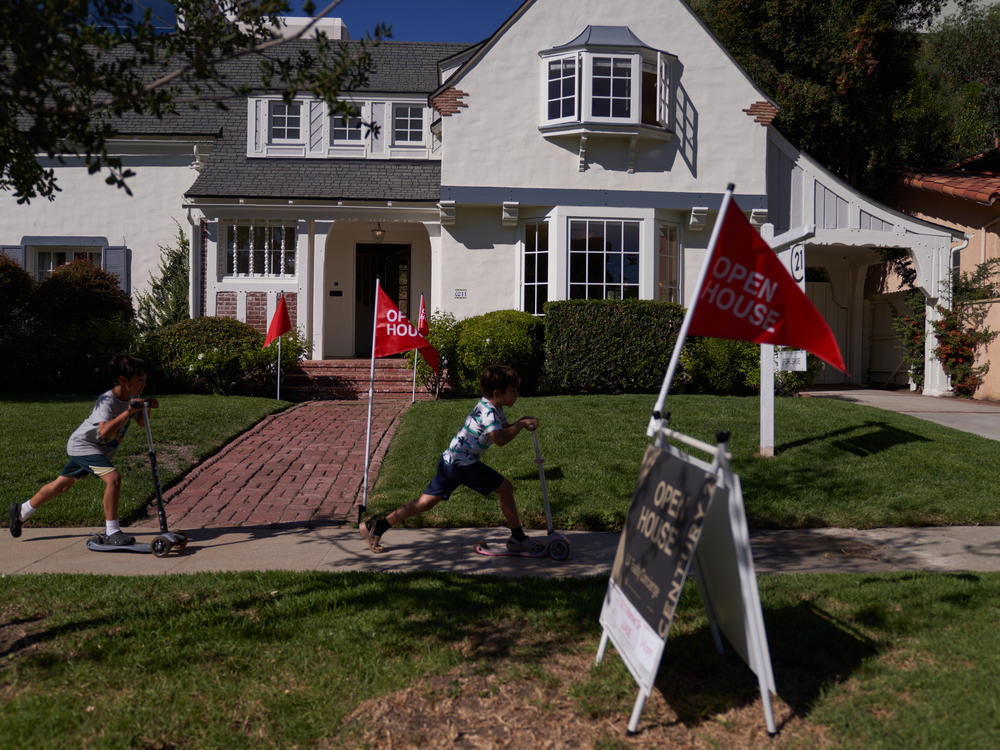 Children ride scooters past a house for sale in Los Angeles. Home sales have slowed as mortgage rates have climbed.