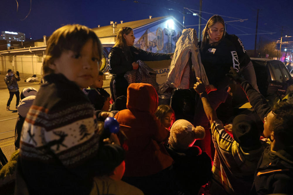 Volunteers with Border Network for Human Rights hand out blankets and supplies to unsheltered migrants outside Sacred Heart Church.