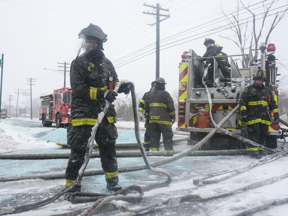 Detroit firefighters try to remove ice from their fire hoses while fighting a warehouse fire on Friday.