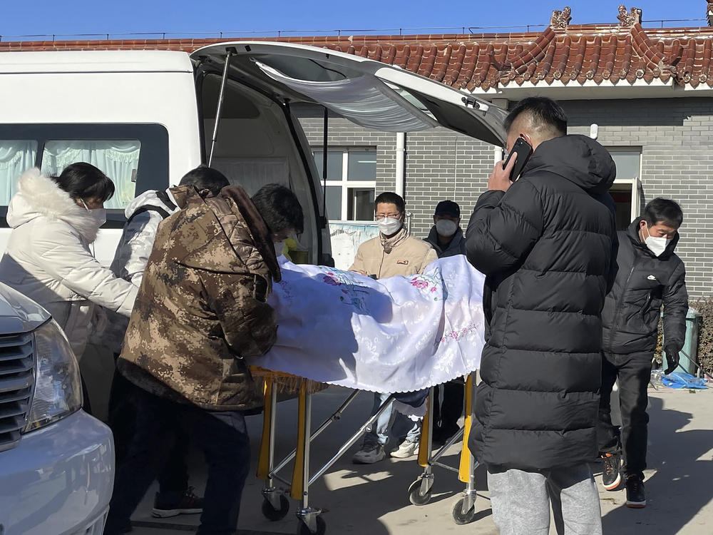 Liang from Beijing, center, looks on as his 82-year-old grandmother is brought in a casket to the Gaobeidian Funeral Home in northern China's Hebei province on Dec. 22, 2022. Liang's grandmother had been unvaccinated when she came down with coronavirus symptoms, and had spent her final days hooked to a respirator in a Beijing ICU.