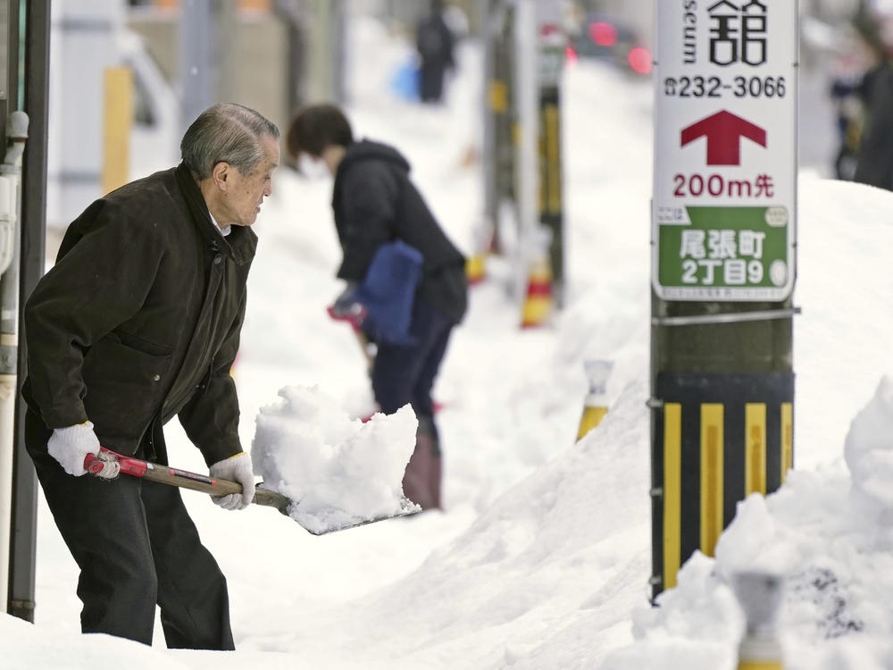 Residents shovel snow off a sidewalk in Kanazawa, Ishikawa prefecture, central Japan, on Dec. 24, 2022.
