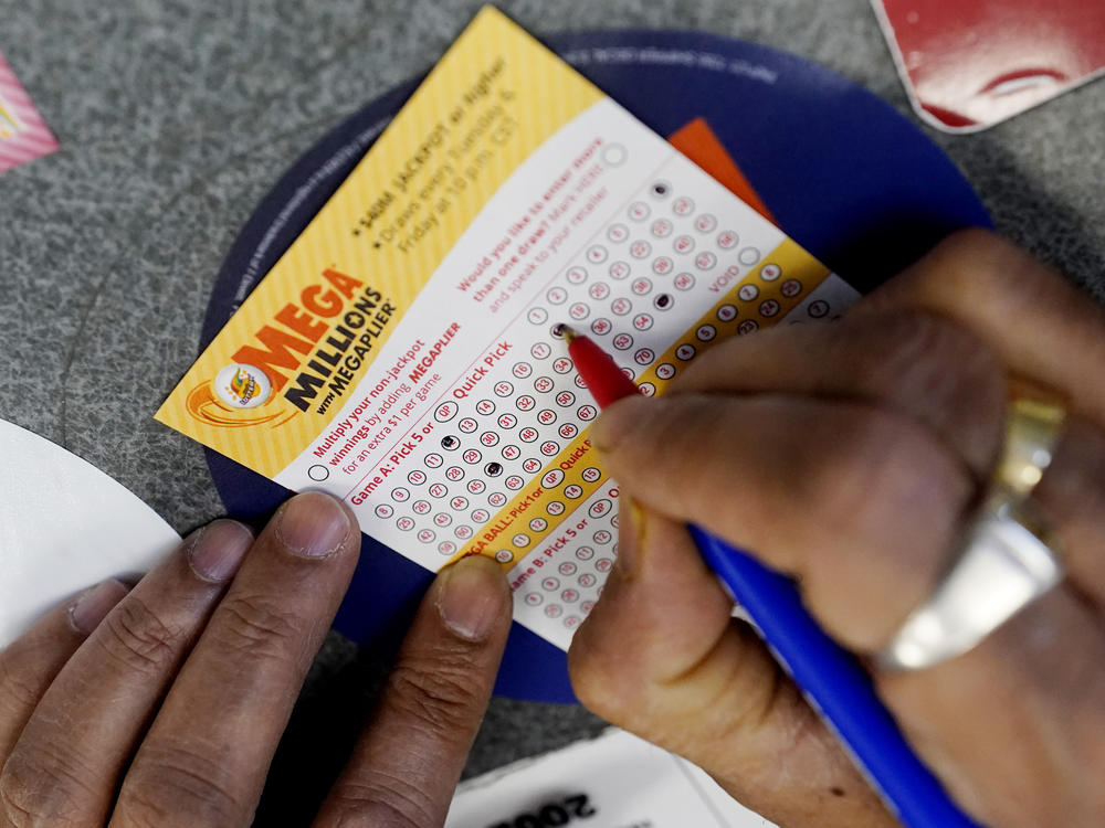 A customer is shown filling out a Mega Millions lottery ticket at a convenience store in Northbrook, Ill., on Jan. 6, 2021. The holiday shopping season, for Mega Millions lottery ticket buyers, at least, is ramping up as officials say the estimated jackpot for the drawing the night of Tuesday, Dec. 27, 2022, has surpassed half a billion dollars.