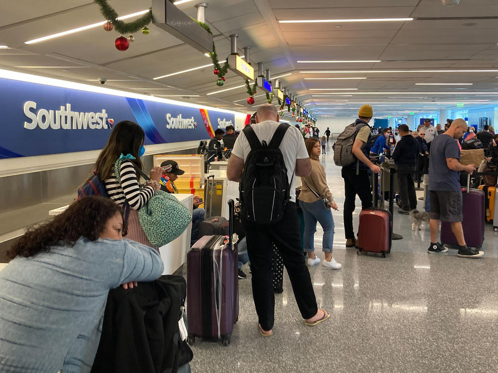 Travelers wait at a Southwest Airlines baggage counter after flight cancellations hit Los Angeles International Airport on Monday. The airline warns it will fly about one-third of its schedule for the next several days.