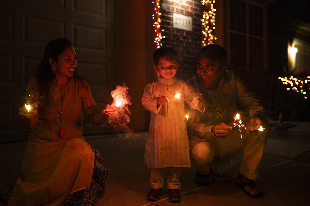 Keerthi Sanivarapu (from left), Ridhay Vemuri and Pavan Vemuri celebrate Diwali (the Hindu festival of lights) by lighting fireworks at their home in Novi, Mich., on Oct. 24, 2022. They also adorn their home with lights, a tradition often confused with Christmas lights in the United States.
