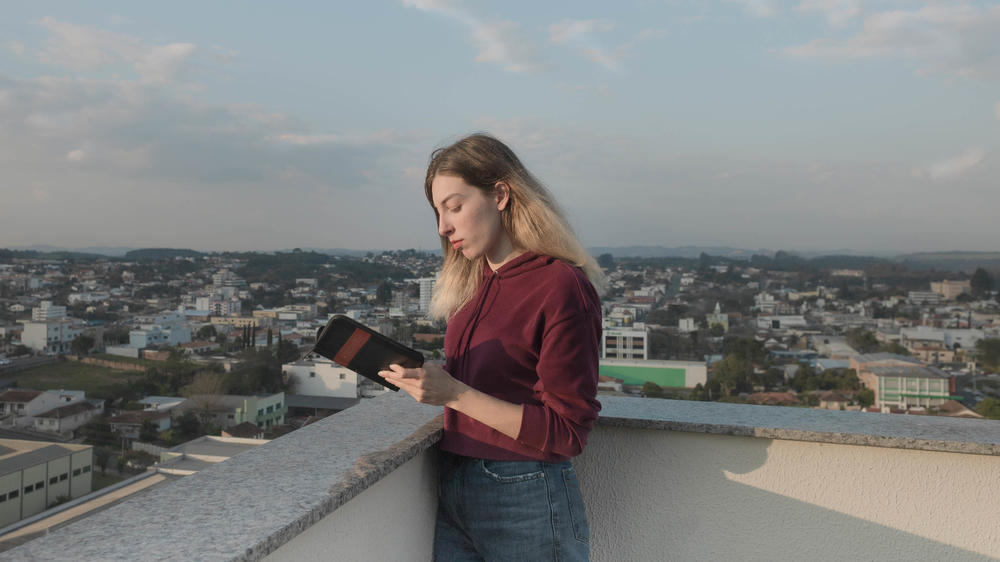 Ukrainian refugee Anastasiia Ivanova reads the Bible on the terrace of the apartment in Prudentópolis, Brazil, where she now lives with her mother and siblings. The devout 22-year-old says her faith is what's helped her get through all of her trials. She brought her Bible with her when the family fled Kharkiv.